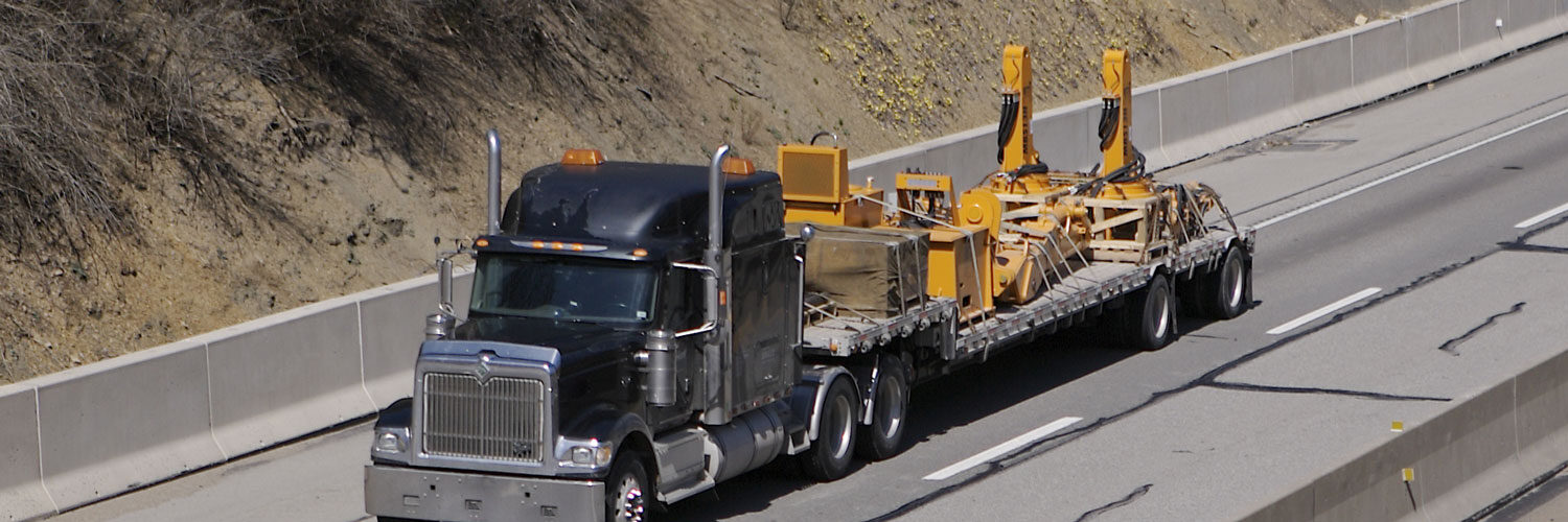 black semi truck on freeway with bed carrying large equipment parts Worldwide Sourcing & Solutions United States, China